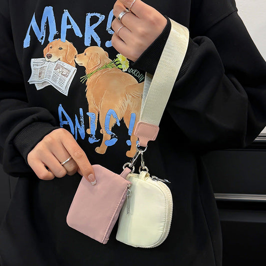 Person holding two small pouches with a black hoodie featuring dog graphics.