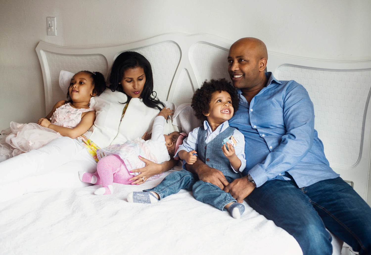 Happy family relaxing together on a bed in a cozy, modern home setting